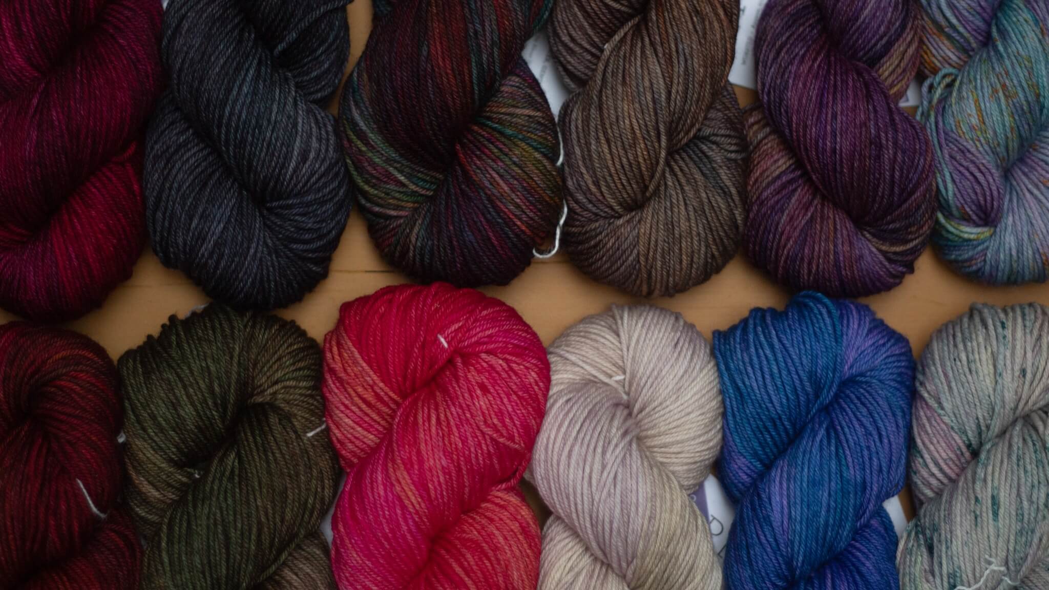 A pile of several hanks of Lucky Tweed yarn in a variety of colors